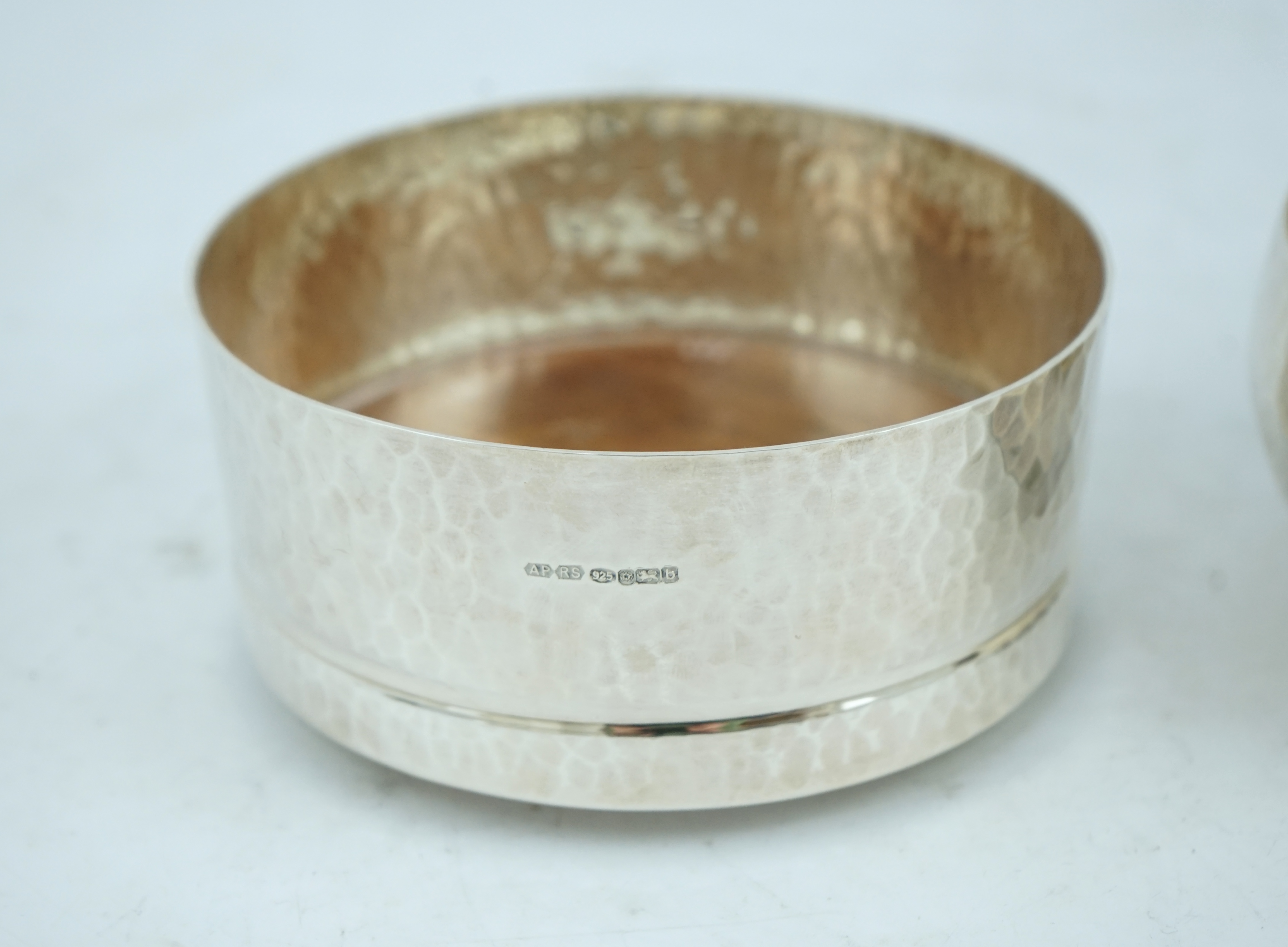 An Elizabeth II planished silver bowl, by Pruden & Smith, Sheffield, 2002, diameter 10cm, together with a similar silver wine coaster by Pruden & Smith, Sheffield, 2001, diameter 10.5cm.